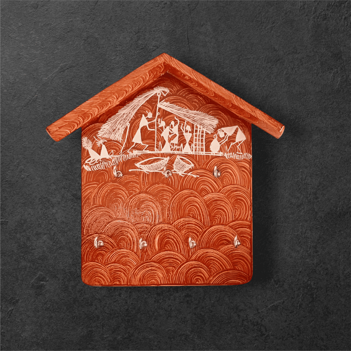 A handcrafted wooden key holder in the shape of a house with Warli art, primarily green with white patterns.