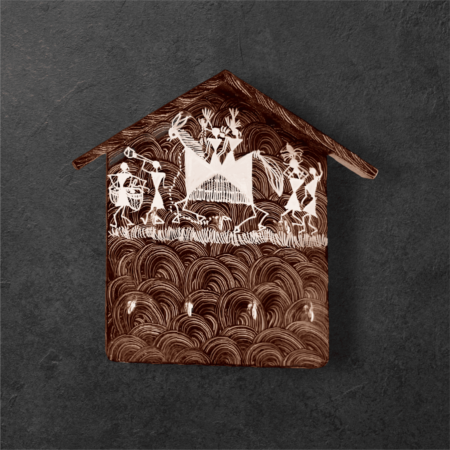 A handcrafted wooden key holder in the shape of a house with Warli art, primarily green with white patterns.