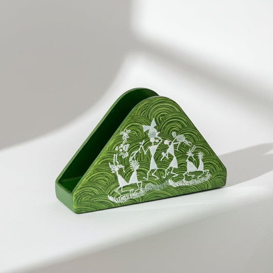 A triangular wooden napkin holder with Warli tribal artwork, predominantly green with white patterns