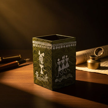 Decorative green pen holder with tribal designs on a wooden surface